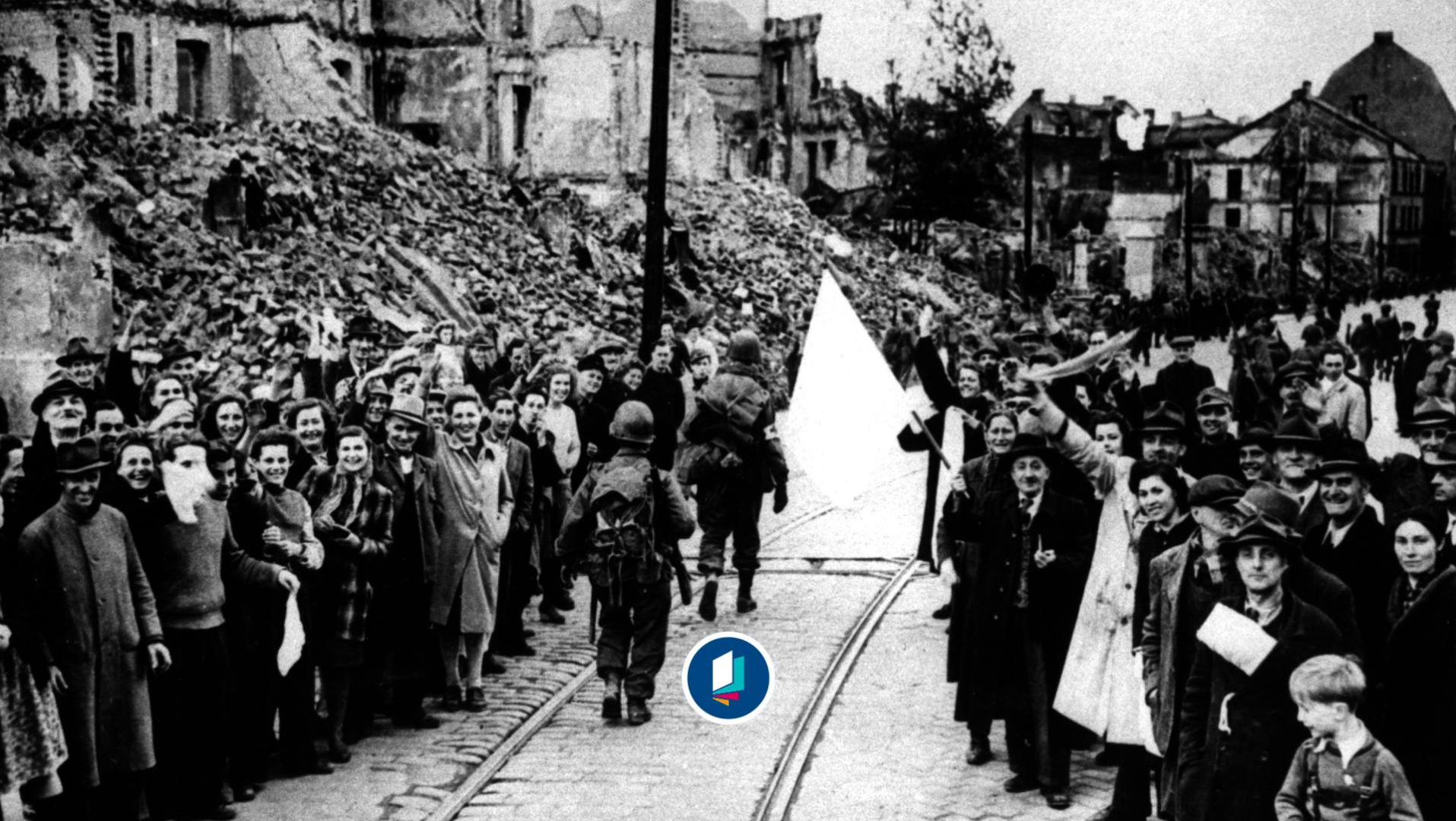 US-Infantristen der 7. U.S. Army marschieren nach der Eroberung der Stadt durch das zerstörte München, begrüßt von der Bevölkerung mit weißer Fahne. 
