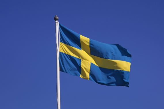 Die schwedische Nationalflagge flattert im Wind vor blauem Himmel