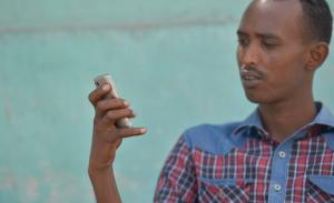 Der Somalier Deeq Ahmed Shire schaut auf sein Smartphone, nachdem die Alhabaab-Miliz alle 3G-Verbindungen gekappt hat - ohne Netz kann er seine Familie nicht erreichen, Mogadischu, 13. Jan. 2014 | © gemeinfrei / David Mutua