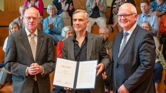 Lutz Seiler (mitte) bekommt von Prof. Dr. Norbert Lammert (li.) und Prof. Dr. Oliver Jahraus (re.) die Urkunde überreicht