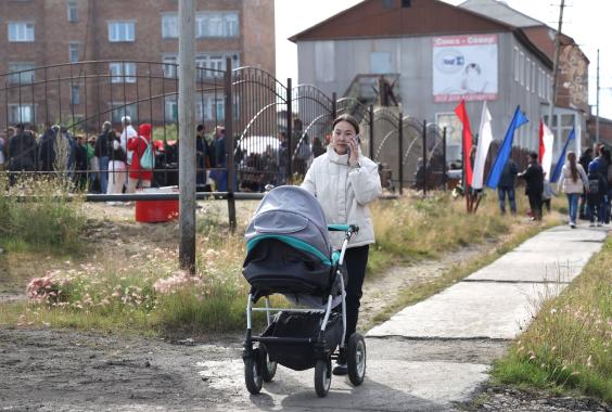 Eine Frau geht mit einem Kinderwagen in einem Dorf in Russland