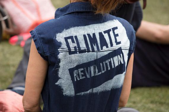 Person trägt Weste mit dem Aufdruck Climate Revolution
